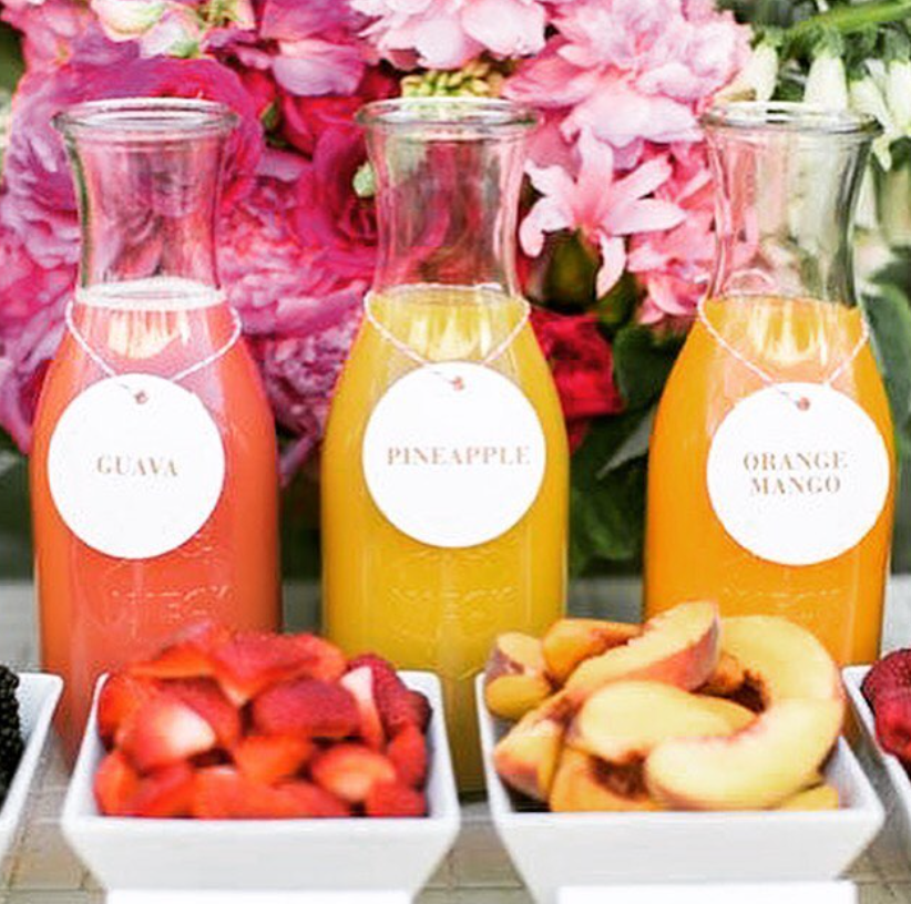 organized baby shower drink station with labeled juice options and garnish bowls