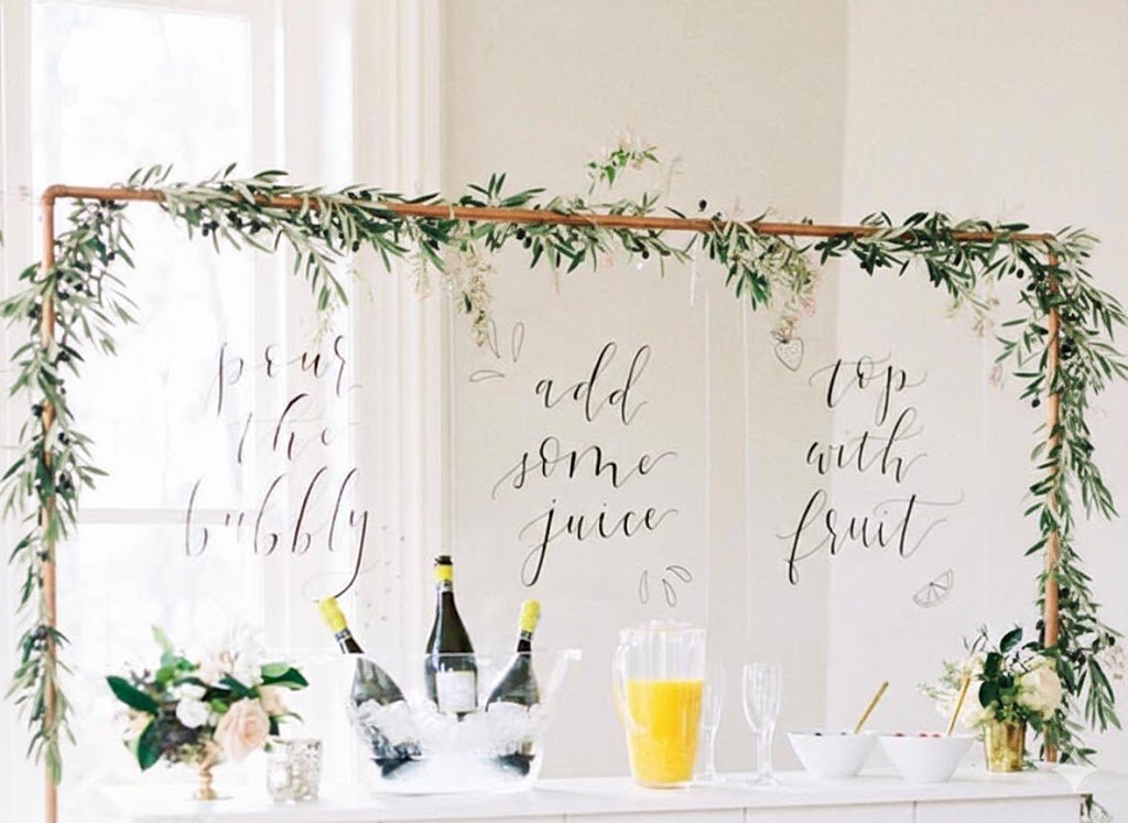 minimalist baby shower bar with olive branch garland, cream porcelain and florals