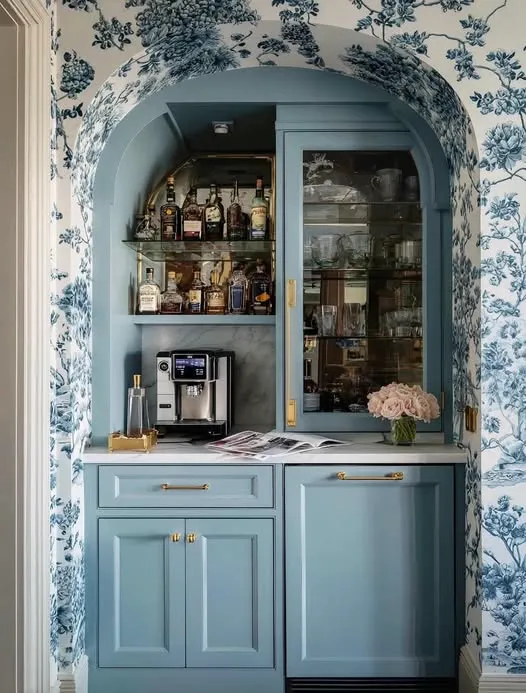 Light blue arched niche with toile wallpaper, glass cabinet door, and coffee wine combination bar