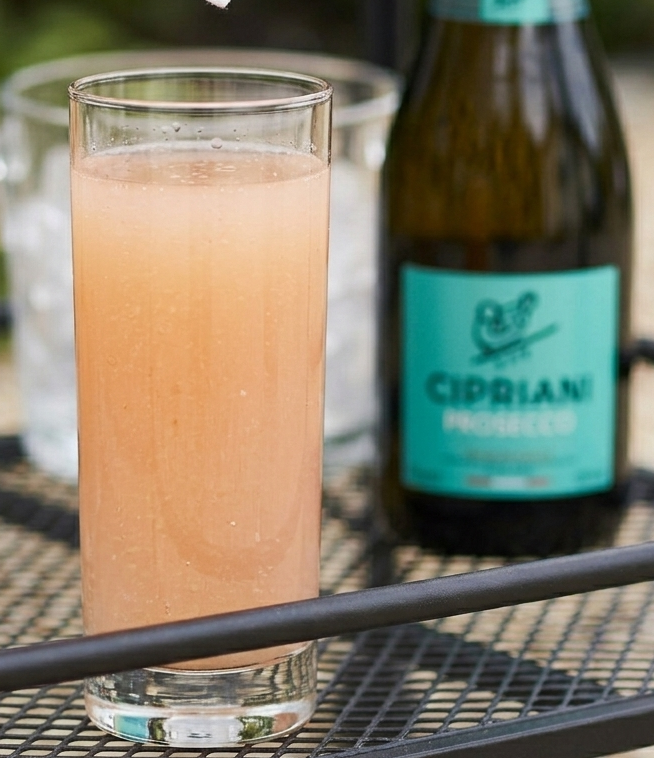 a bellini cocktail with a bottle of prosecco
